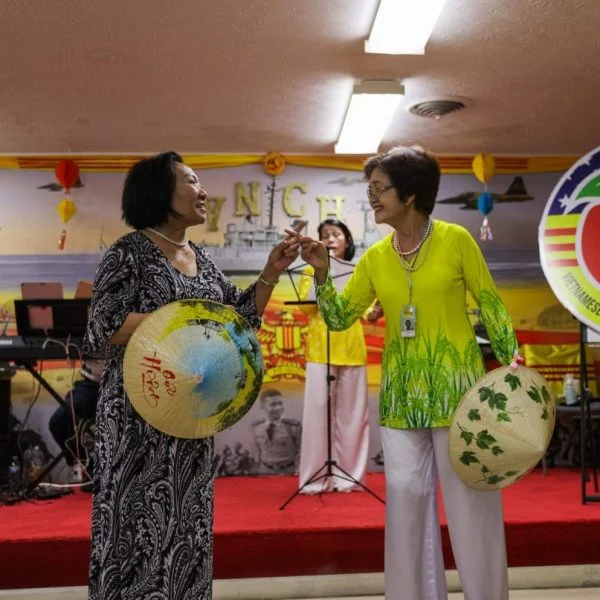 Photograph of two ladies smiling on the stage of the Vietnamese Community center featured in The Southside story map